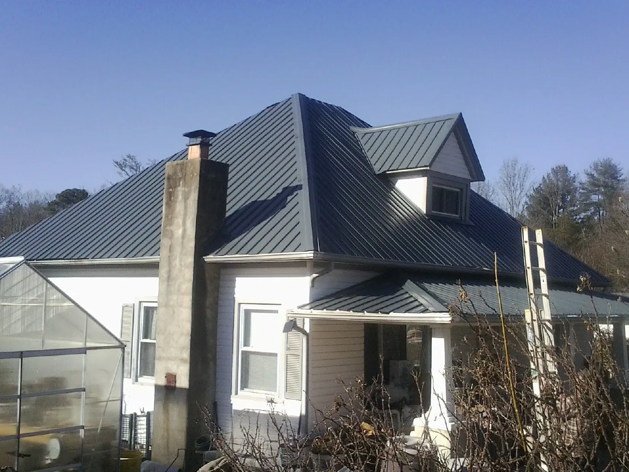 Dark blue standing seam metal roof on a white farmhouse with dormer — Slate & Tile Roof Repair by Roofing Brothers in Green Springs