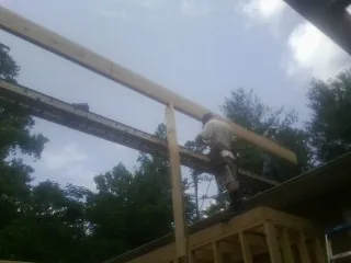 Carpenter setting a ridge beam over a new addition frame — Ice Dam Removal by Roofing Brothers in Green Springs