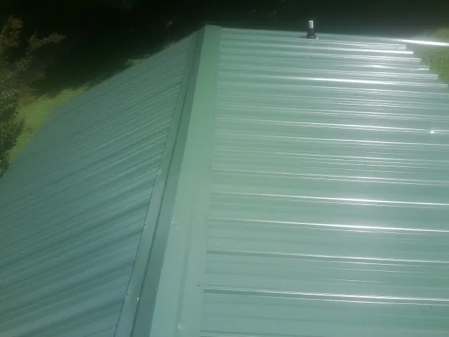 New green metal panels meeting at the ridge of a roof — Flat Roof Repair work by our crew in Green Springs