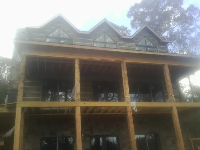 Dormers and porch framing on a large log home under construction — Roof Coating work by our crew in Green Springs