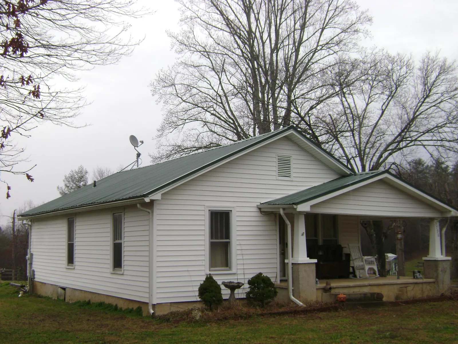 Green metal roof on a white bungalow with a side porch in Green Springs