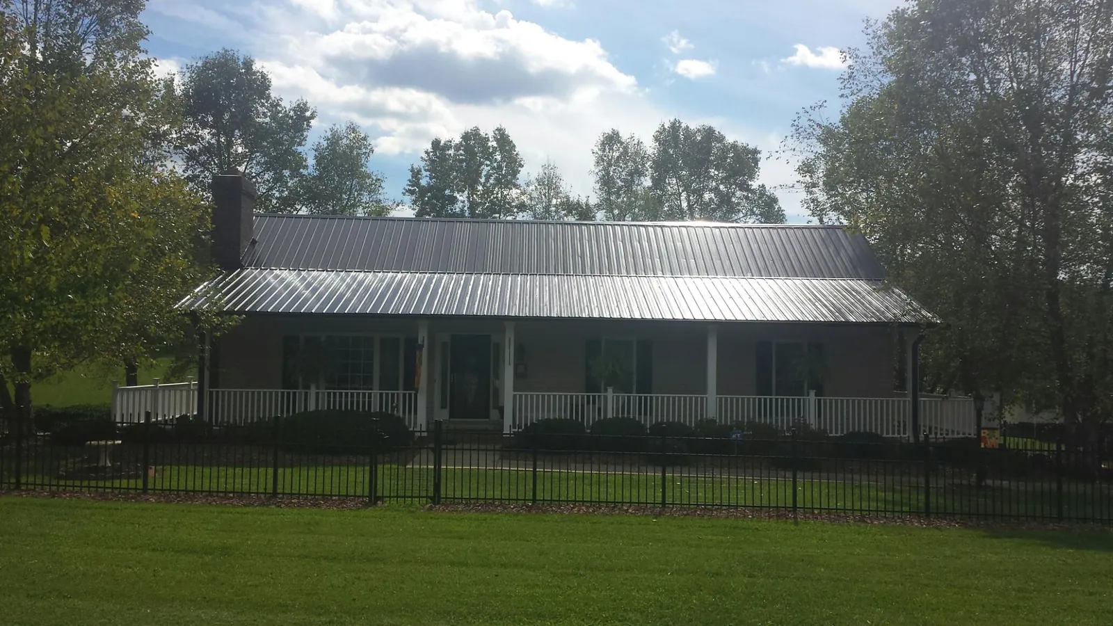 Gray metal roof on a brick ranch with a full width front porch — Gutter Guard Installation work by our crew in Green Springs