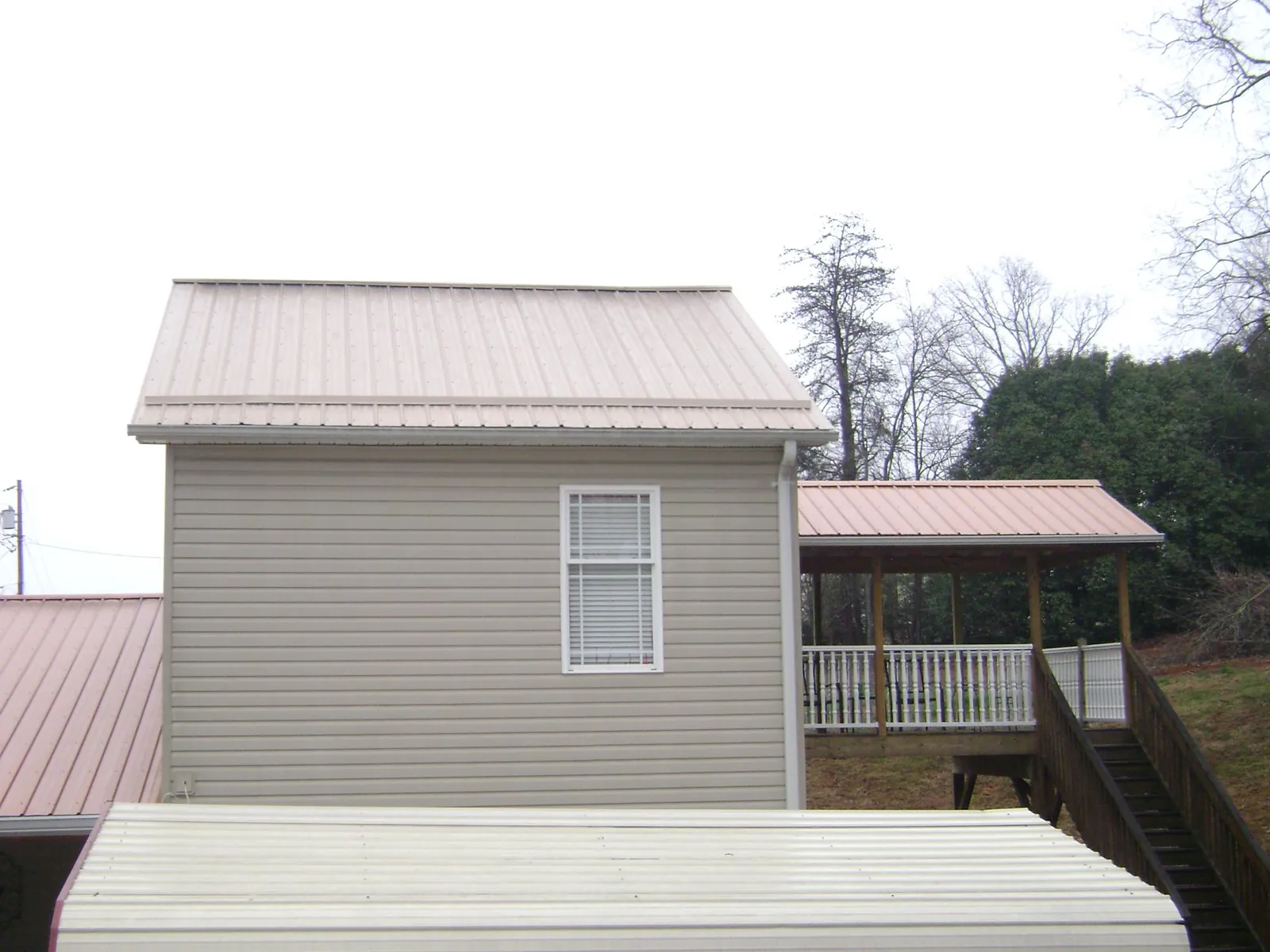 Tan metal roofs on a two story addition and attached porch, from a Roof Replacement job in Green Springs