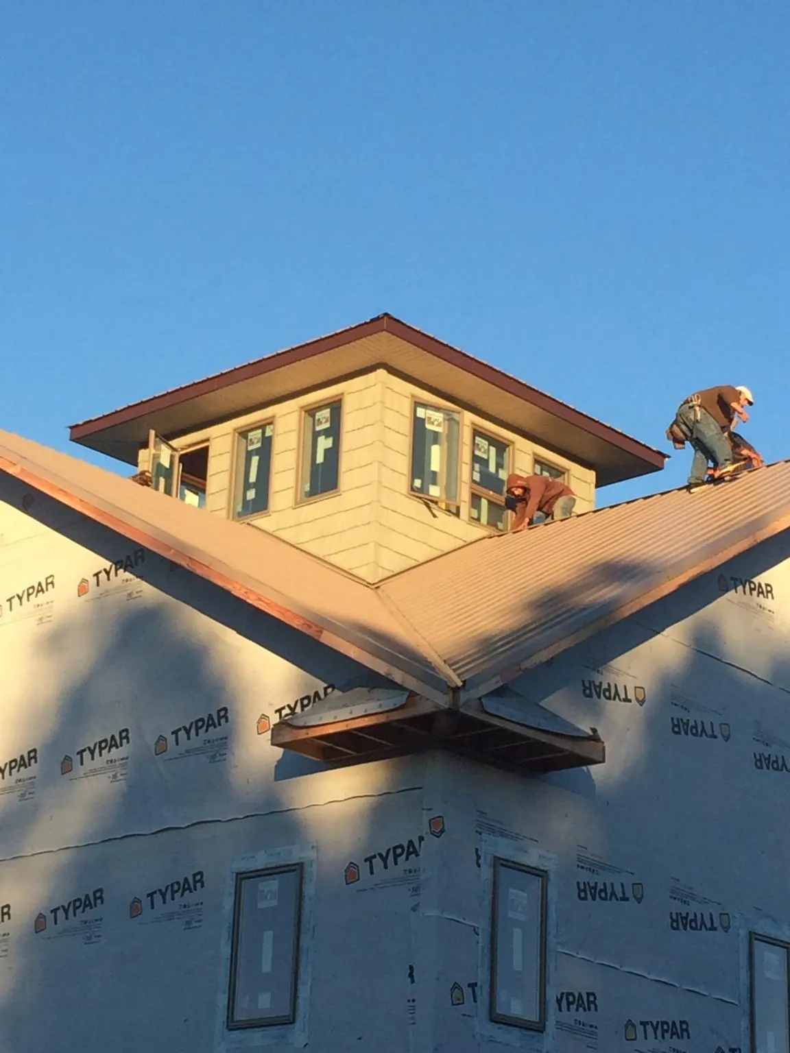 Roofers working around a rooftop cupola on a new metal roof at sunset — Roof Waterproofing in Green Springs by Roofing Brothers